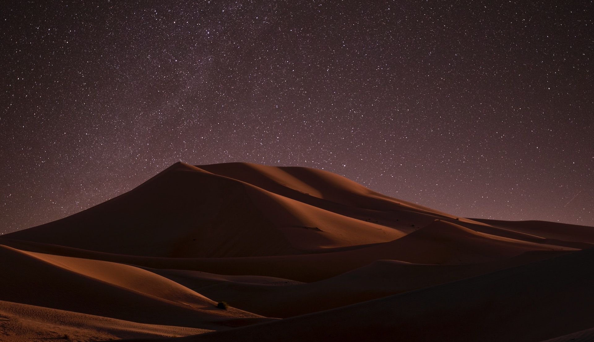 Photo of sand dunes at night, under a starry sky