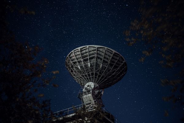 A photo of a radio telescope at night, with background of stars in the sky