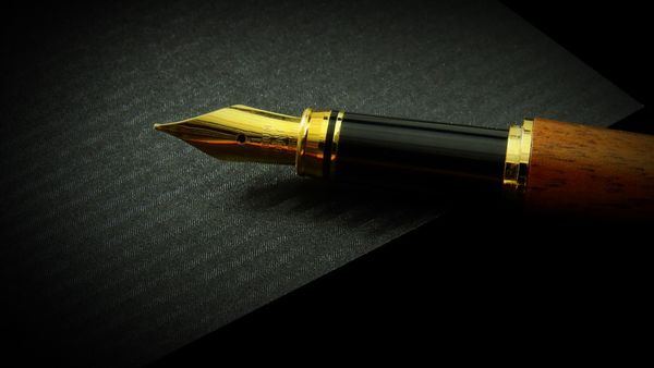 An expensive looking gold-tipped fountain pen on textured black paper